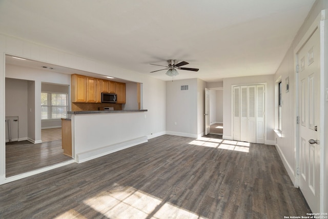 unfurnished living room with dark hardwood / wood-style flooring and ceiling fan