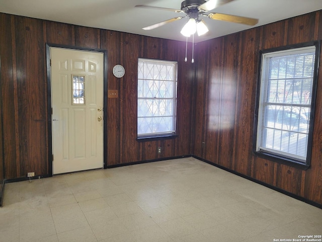 entrance foyer featuring ceiling fan and wood walls