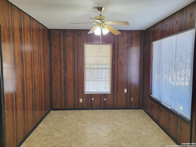 unfurnished room featuring ceiling fan and wood walls