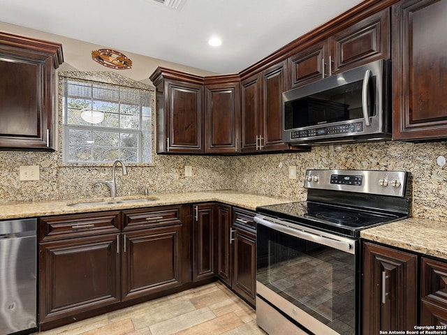 kitchen with decorative backsplash, sink, stainless steel appliances, and light stone counters