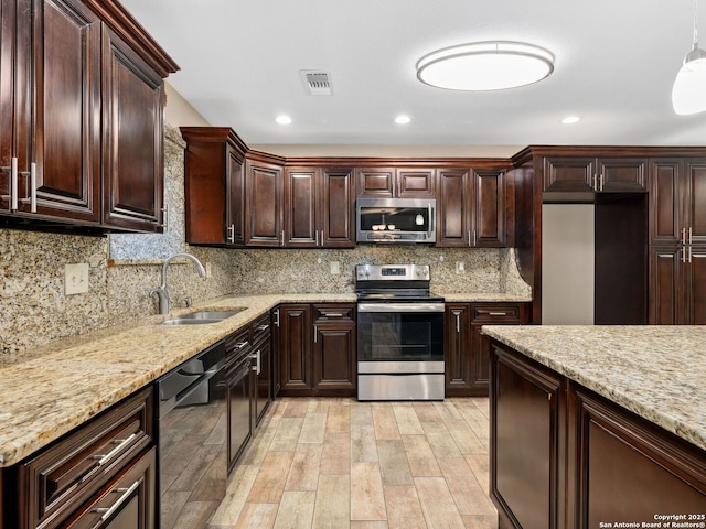 kitchen featuring light stone countertops, sink, backsplash, appliances with stainless steel finishes, and light wood-type flooring