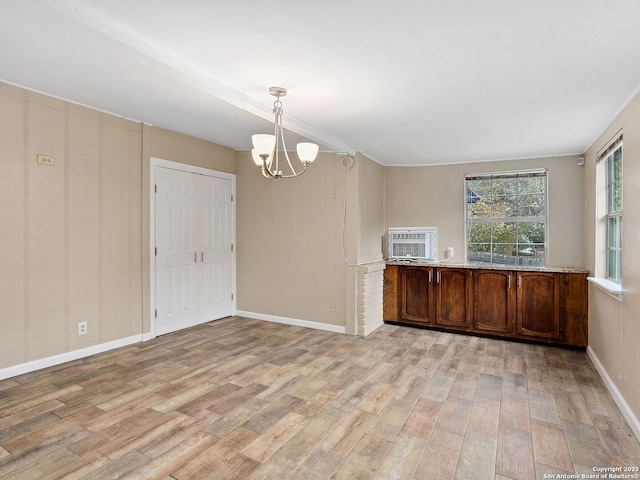 kitchen featuring a notable chandelier, light stone countertops, hanging light fixtures, and light hardwood / wood-style flooring