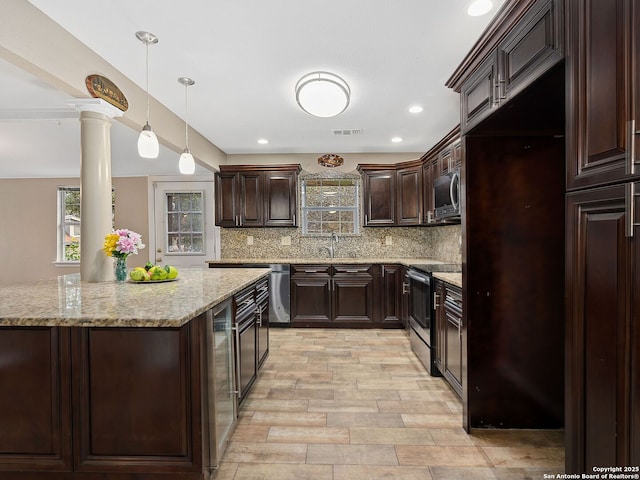 kitchen featuring hanging light fixtures, ornate columns, appliances with stainless steel finishes, tasteful backsplash, and dark brown cabinetry