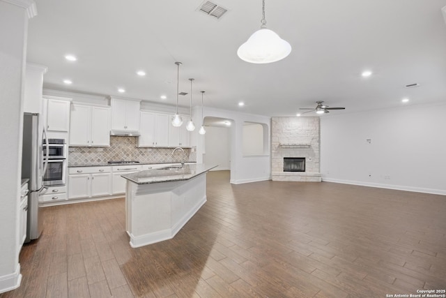 kitchen featuring white cabinets, a kitchen island with sink, hanging light fixtures, and stainless steel appliances