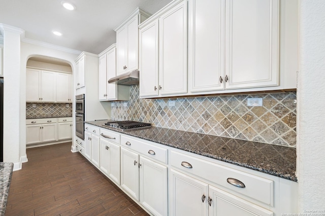 kitchen with backsplash, dark stone counters, white cabinets, dark hardwood / wood-style floors, and appliances with stainless steel finishes