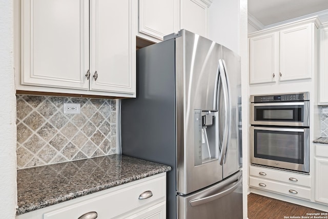 kitchen featuring white cabinetry, tasteful backsplash, dark hardwood / wood-style flooring, dark stone countertops, and appliances with stainless steel finishes