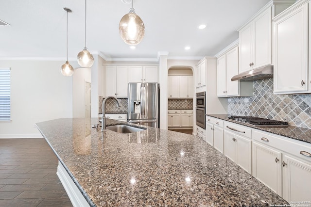 kitchen featuring appliances with stainless steel finishes, dark stone counters, a spacious island, sink, and hanging light fixtures