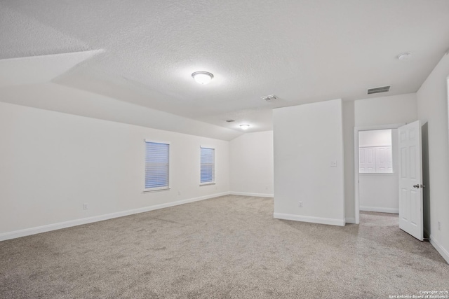 spare room with a textured ceiling and vaulted ceiling