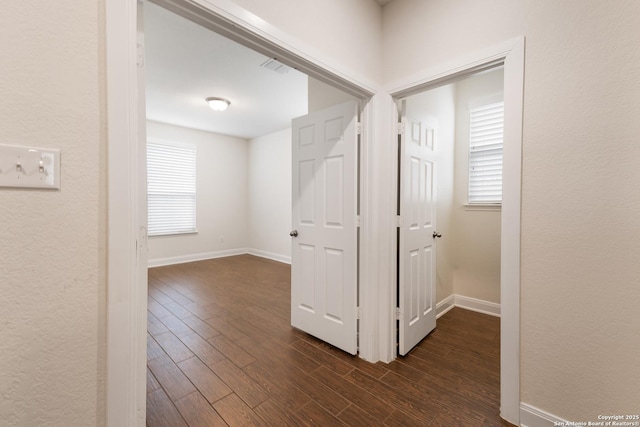 corridor featuring a healthy amount of sunlight and dark wood-type flooring