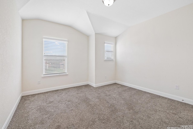 unfurnished room featuring carpet floors and vaulted ceiling