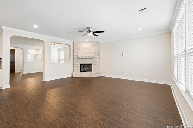 unfurnished living room featuring ceiling fan, dark hardwood / wood-style floors, a stone fireplace, and a wealth of natural light