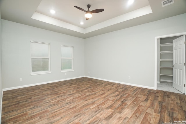 empty room with a tray ceiling, ceiling fan, and hardwood / wood-style flooring