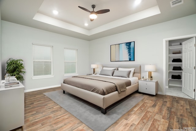 bedroom with a tray ceiling, ceiling fan, and hardwood / wood-style flooring