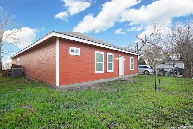 view of side of property featuring a lawn and central AC