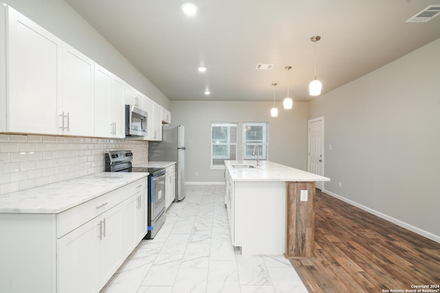 kitchen featuring white cabinets, appliances with stainless steel finishes, hanging light fixtures, and sink