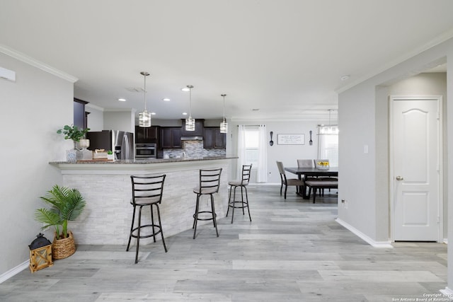 kitchen featuring a kitchen breakfast bar, kitchen peninsula, crown molding, and appliances with stainless steel finishes