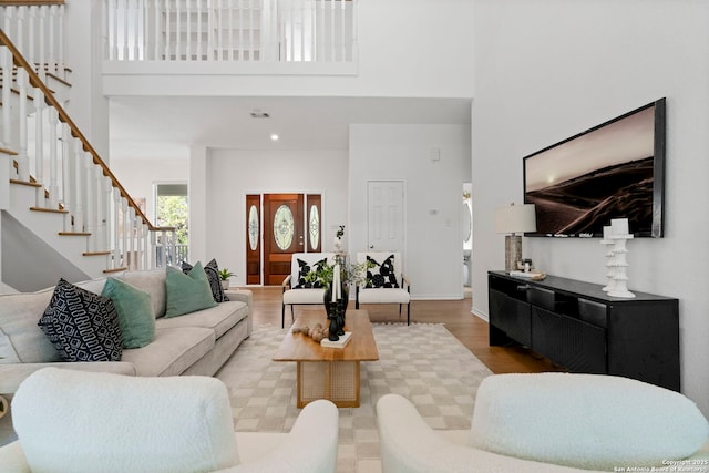 living room with light hardwood / wood-style flooring and a towering ceiling