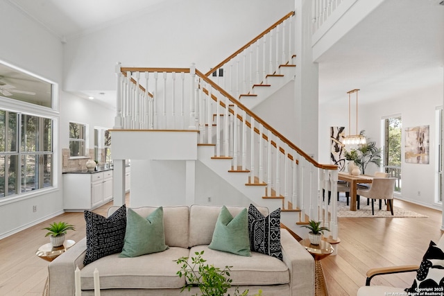 living room featuring a high ceiling, an inviting chandelier, light hardwood / wood-style flooring, and ornamental molding