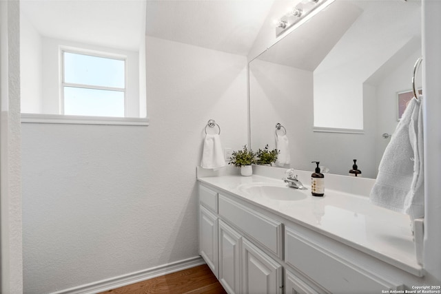 bathroom with vanity, vaulted ceiling, and hardwood / wood-style flooring