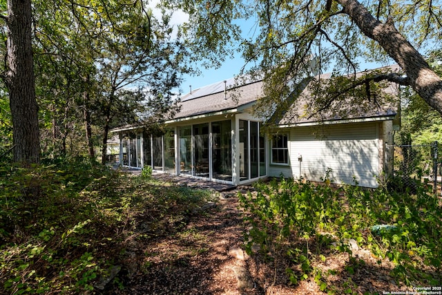 rear view of house with a sunroom and solar panels