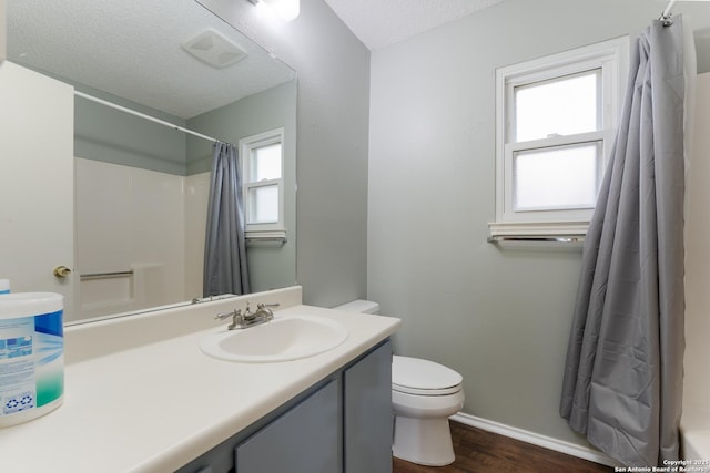 bathroom with vanity, a healthy amount of sunlight, toilet, and a textured ceiling