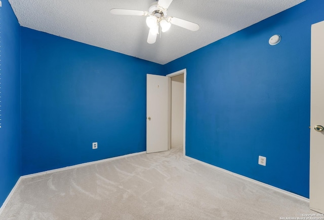 spare room with ceiling fan, light colored carpet, and a textured ceiling