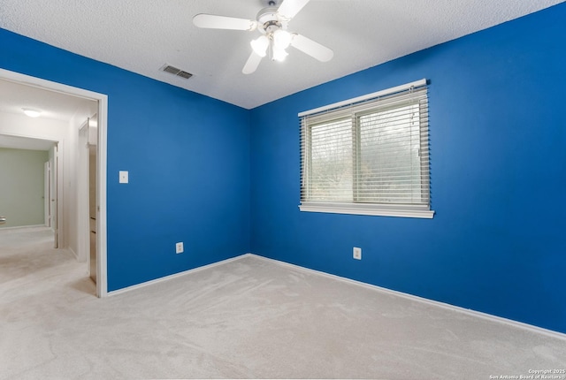 carpeted empty room with ceiling fan and a textured ceiling