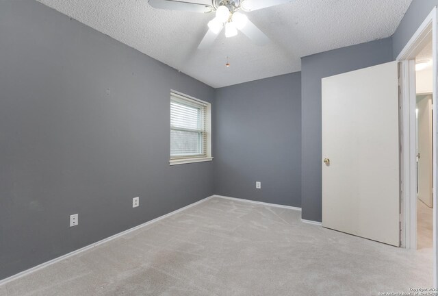 unfurnished bedroom featuring light carpet, a textured ceiling, and ceiling fan