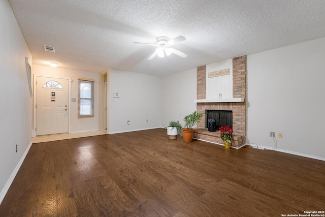 unfurnished living room featuring hardwood / wood-style flooring, ceiling fan, a textured ceiling, and a brick fireplace