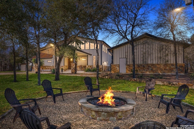 back of property featuring a fire pit and a lawn