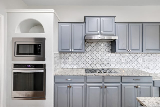 kitchen featuring decorative backsplash, light stone countertops, and appliances with stainless steel finishes