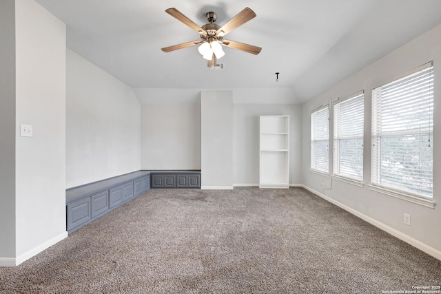 empty room with vaulted ceiling, carpet floors, built in features, and ceiling fan