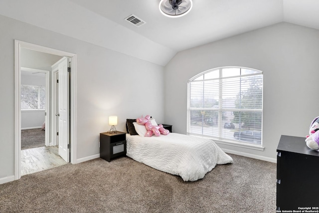 bedroom featuring light carpet, vaulted ceiling, and multiple windows