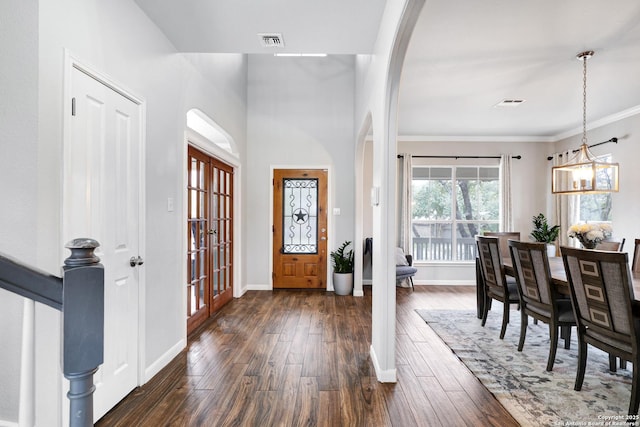 foyer entrance with french doors, an inviting chandelier, dark wood-type flooring, and crown molding