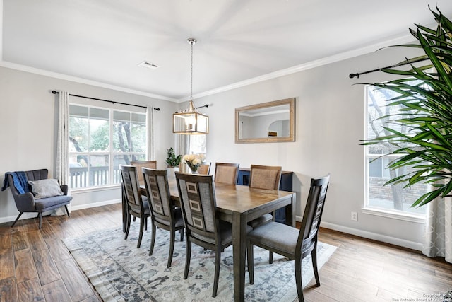 dining area with hardwood / wood-style flooring, ornamental molding, and a chandelier