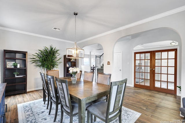 dining room featuring hardwood / wood-style flooring, an inviting chandelier, ornamental molding, and french doors