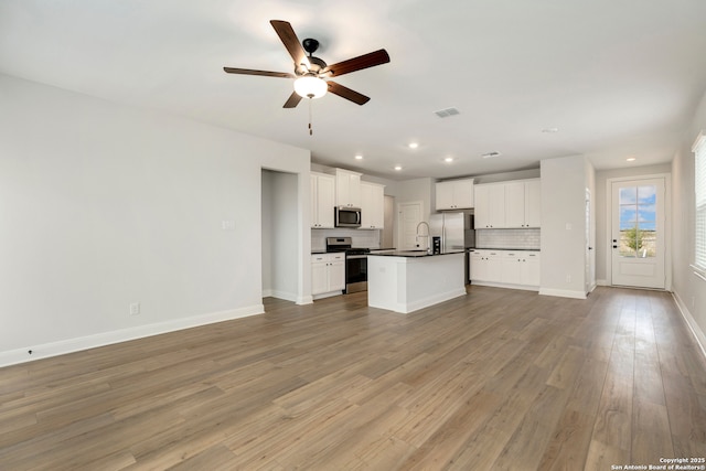 kitchen featuring white cabinetry, light hardwood / wood-style flooring, backsplash, an island with sink, and appliances with stainless steel finishes