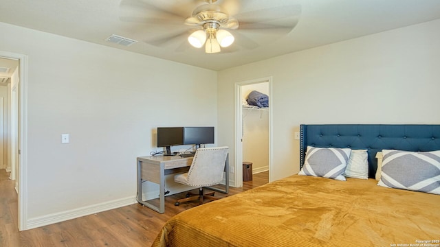 bedroom featuring hardwood / wood-style floors, ceiling fan, a walk in closet, and a closet