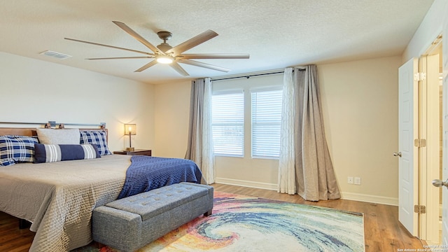 bedroom featuring ceiling fan, wood-type flooring, and a textured ceiling