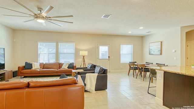 living room with ceiling fan, light parquet floors, and a textured ceiling