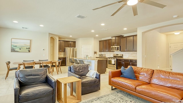 tiled living room featuring ceiling fan and sink