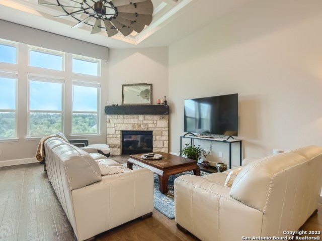 living room featuring ceiling fan, a fireplace, and wood-type flooring