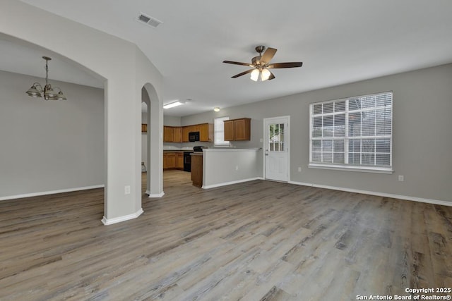 unfurnished living room with light hardwood / wood-style flooring and ceiling fan with notable chandelier