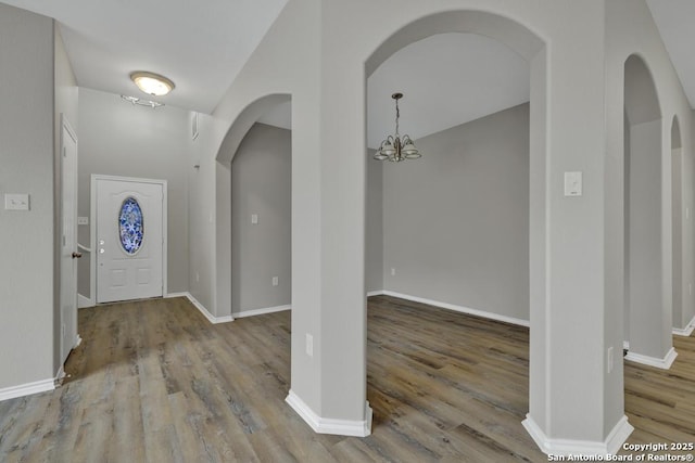 entryway with wood-type flooring and an inviting chandelier