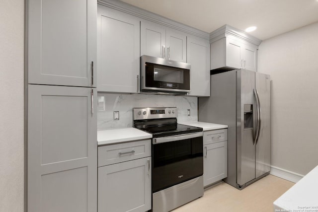 kitchen with stainless steel appliances, decorative backsplash, and gray cabinets