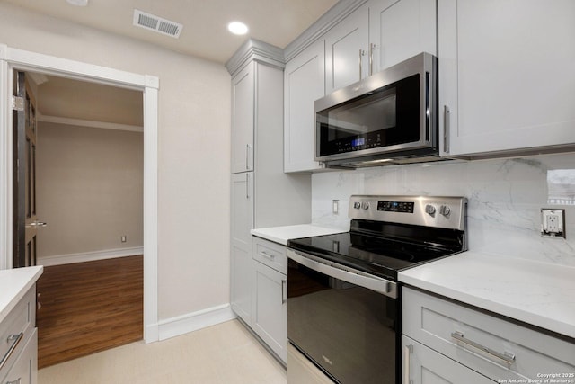 kitchen with appliances with stainless steel finishes, backsplash, and light stone countertops