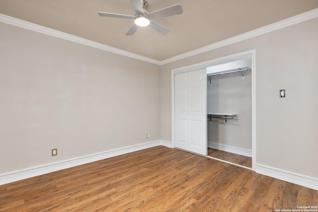 unfurnished bedroom with hardwood / wood-style floors, a closet, ceiling fan, and crown molding