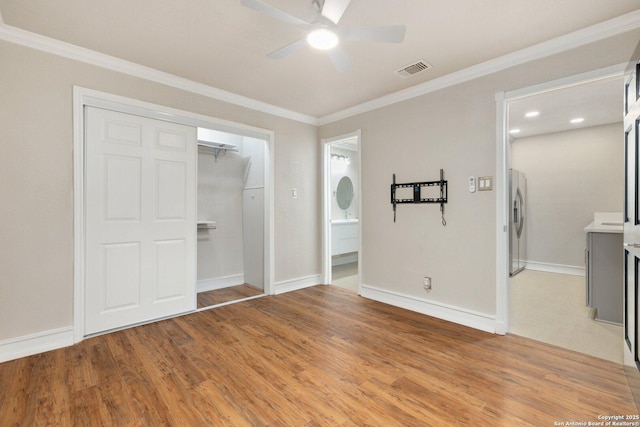 unfurnished bedroom with connected bathroom, a closet, ornamental molding, ceiling fan, and stainless steel refrigerator with ice dispenser