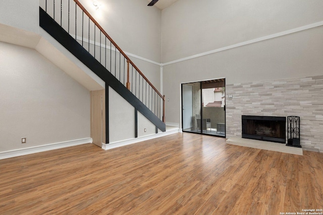 unfurnished living room featuring a tiled fireplace, light hardwood / wood-style floors, and a high ceiling