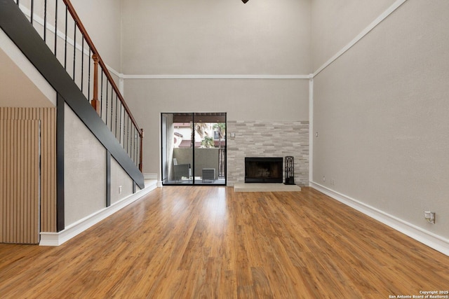 unfurnished living room featuring a high ceiling, a tile fireplace, and hardwood / wood-style floors